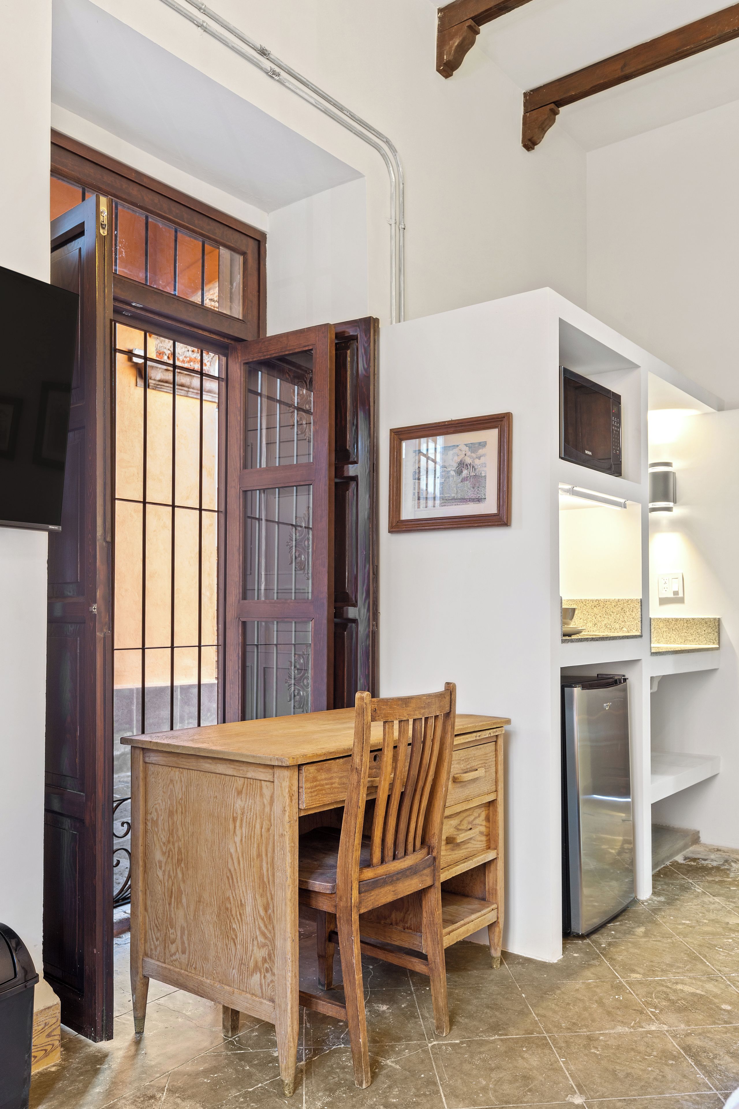 A compact kitchen with a wooden table and chairs, a built-in microwave, and a small refrigerator.