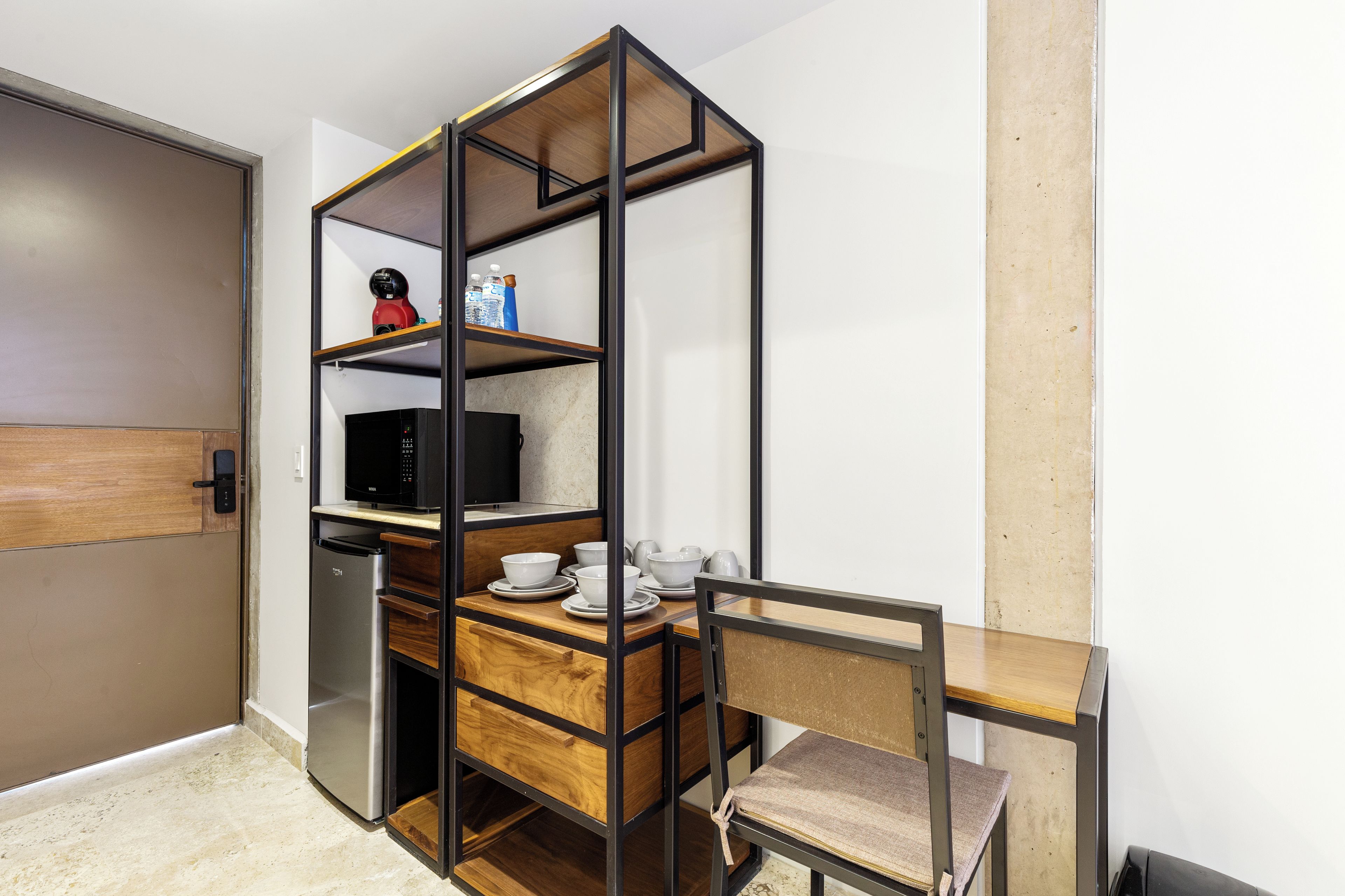 A compact kitchenette with a built-in microwave, a small refrigerator, and a wooden dining table with chairs.