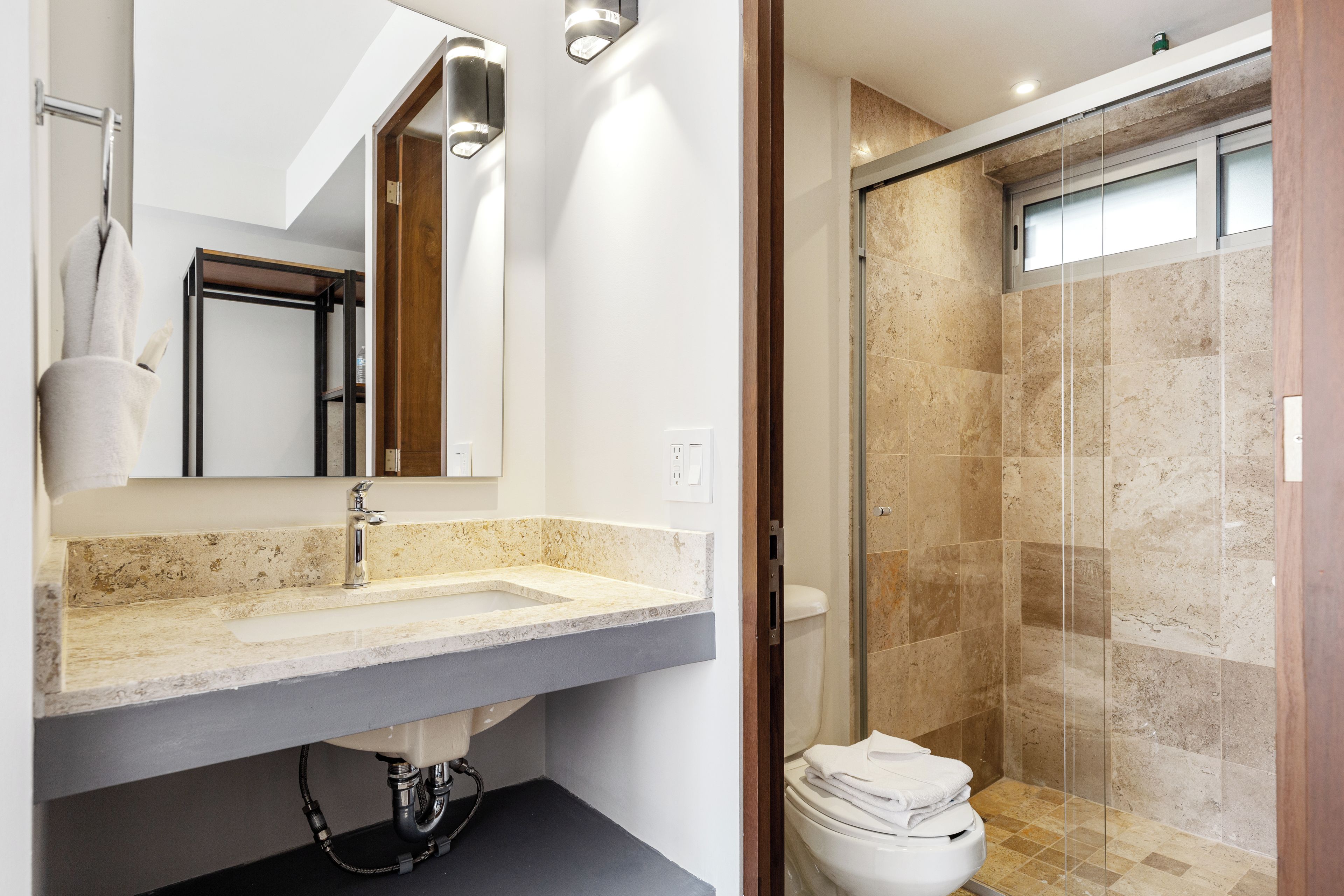 A modern bathroom with a large mirror, a sink, and a shower area.