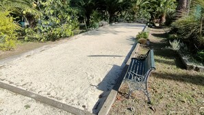 A gravel parking area with a bench and a pathway lined with trees and shrubs. - Charming House : Swimming pool, Tennis court, Greenery, Near the sea (Bormes-les-Mimosas)