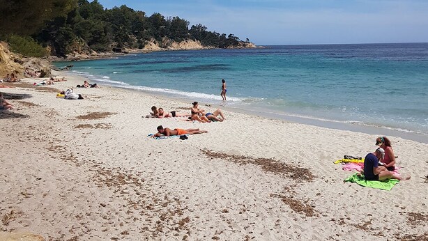 A beach with people sunbathing and swimming, clear skies, and a calm sea. - Charming House : Swimming pool, Tennis court, Greenery, Near the sea (Bormes-les-Mimosas)