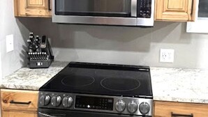 A kitchen with wooden cabinets, a built-in microwave, and a black stove. - Salmon Goldbug Cottage, hot tub sleeps 8 (Salmon)