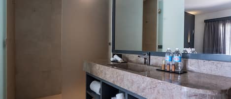 A modern bathroom with a large mirror, two sinks, and a walk-in shower.
