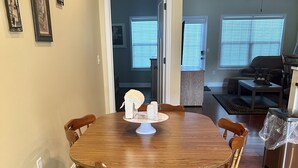 Un comedor con una mesa y sillas de madera, un centro de mesa blanco y cuadros en la pared.