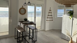 A modern kitchen with a dining area, large windows with ocean views, and a hanging light fixture. - BALERMA BEACH (El Ejido)