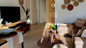 A modern living room with a flat-screen TV, wooden furniture, a round coffee table, and a sofa with patterned cushions. - BALERMA BEACH (El Ejido)