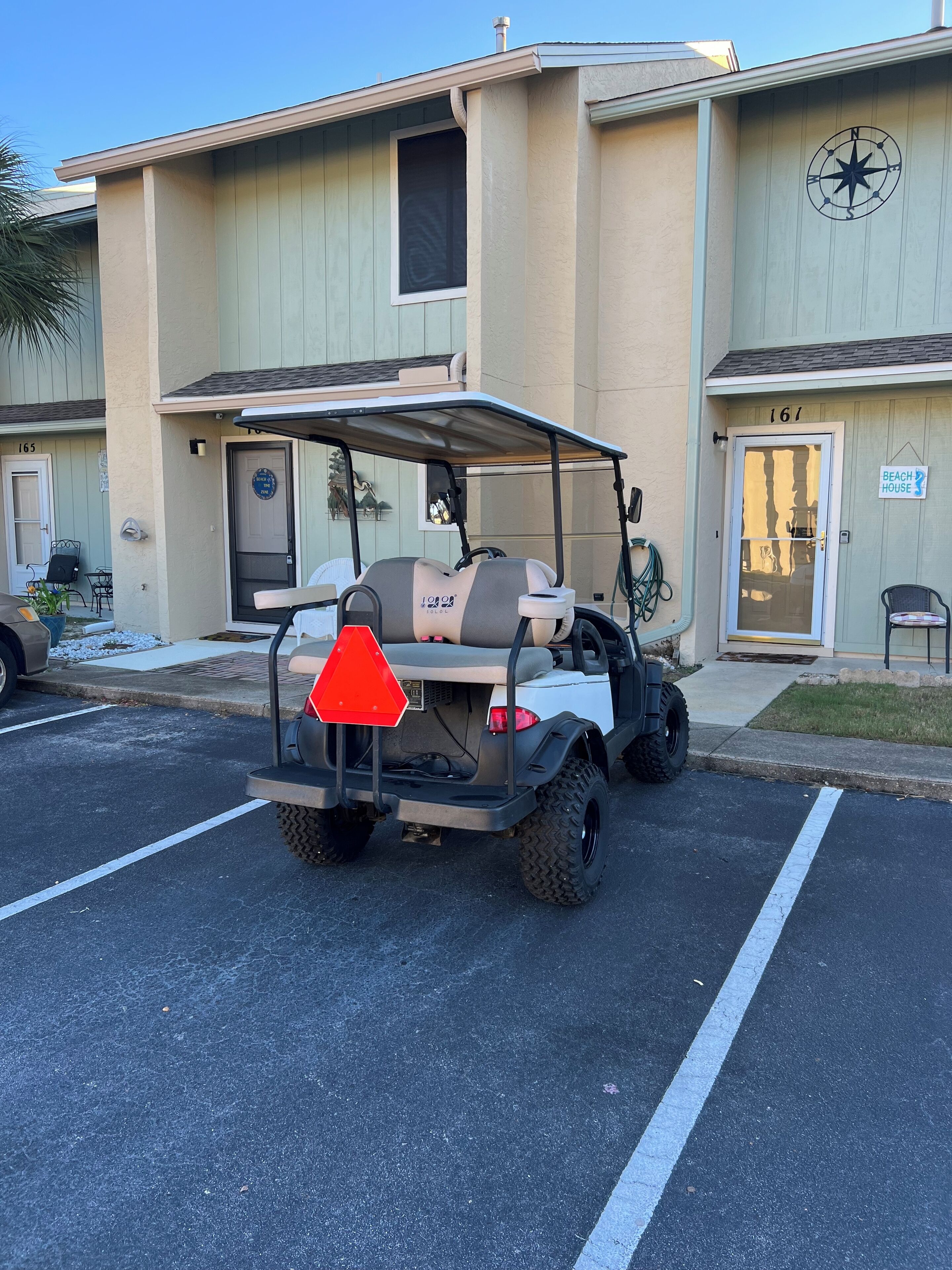 A golf cart parked in a parking lot with a building in the background.