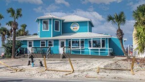 A two-story building with a blue exterior and a white roof, featuring a circular emblem on the front. - Spacious 2BR/2.5BA Two-Story Beach House, Pet Friendly, FREE Golf Cart Included (Panama City Beach)