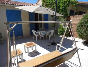 Eine Terrasse mit Schaukel, Tisch und Stühlen.