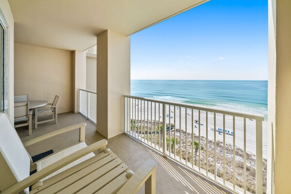 Ein Balkon mit Blick auf den Strand, einem Tisch und einer Bank.