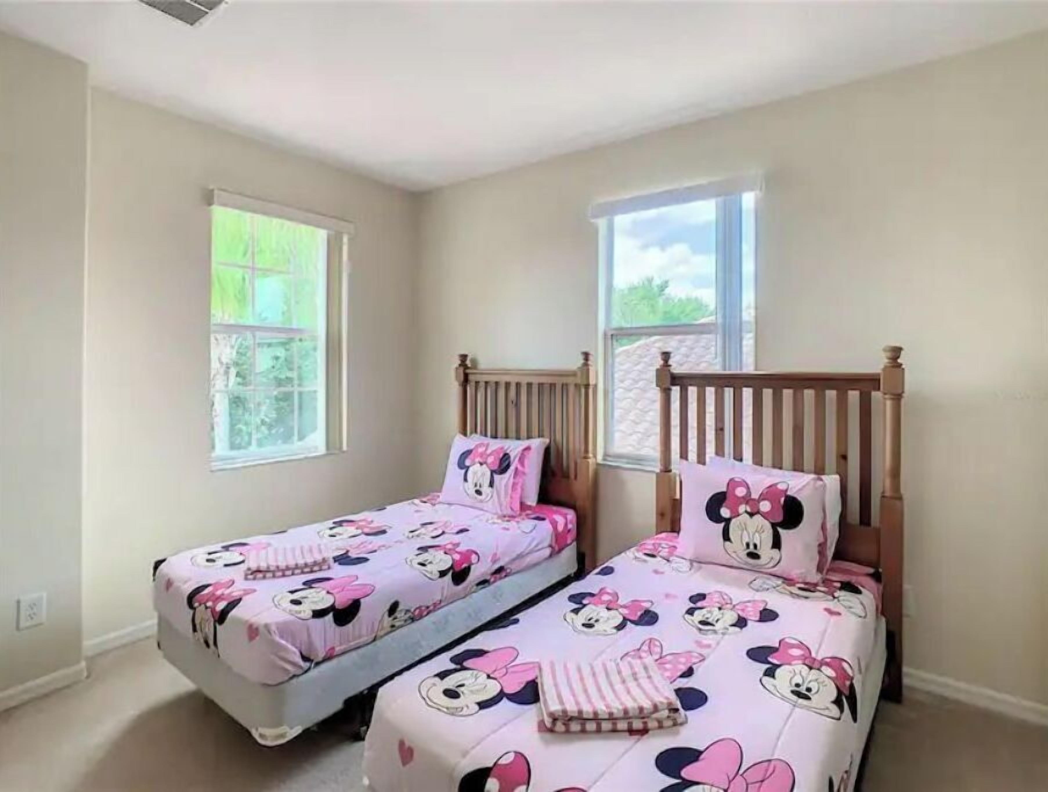 Ein Schlafzimmer mit zwei Einzelbetten, jeweils mit Bettzeug im Minnie Maus Design.