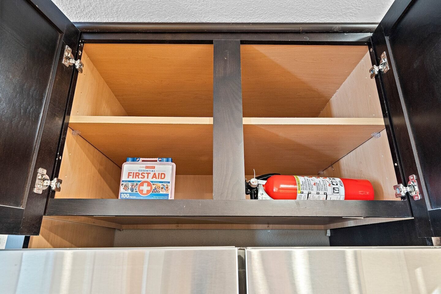 Un meuble contenant une trousse de premiers secours et un extincteur.