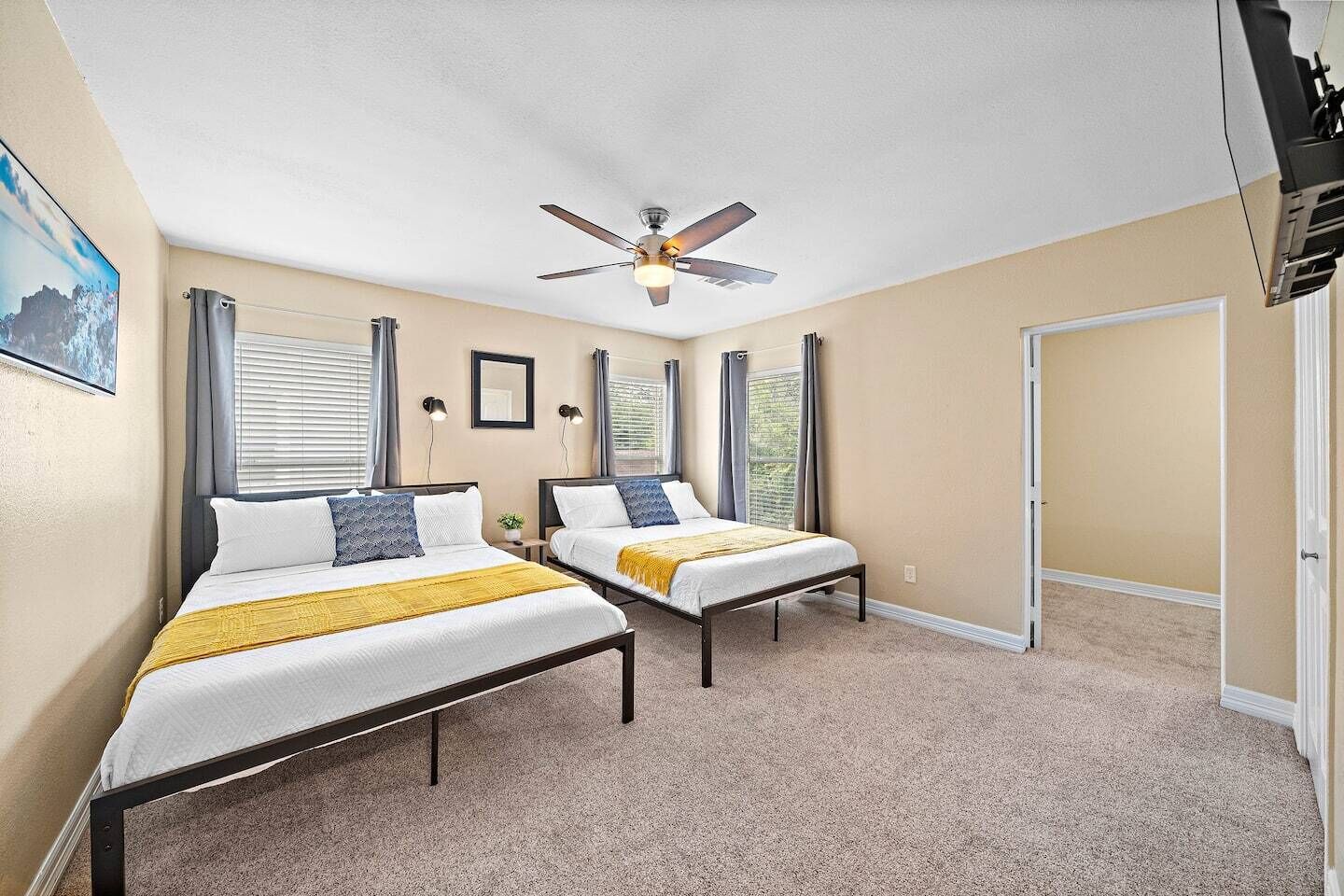 A bedroom with two beds, a ceiling fan, and a door to a balcony.