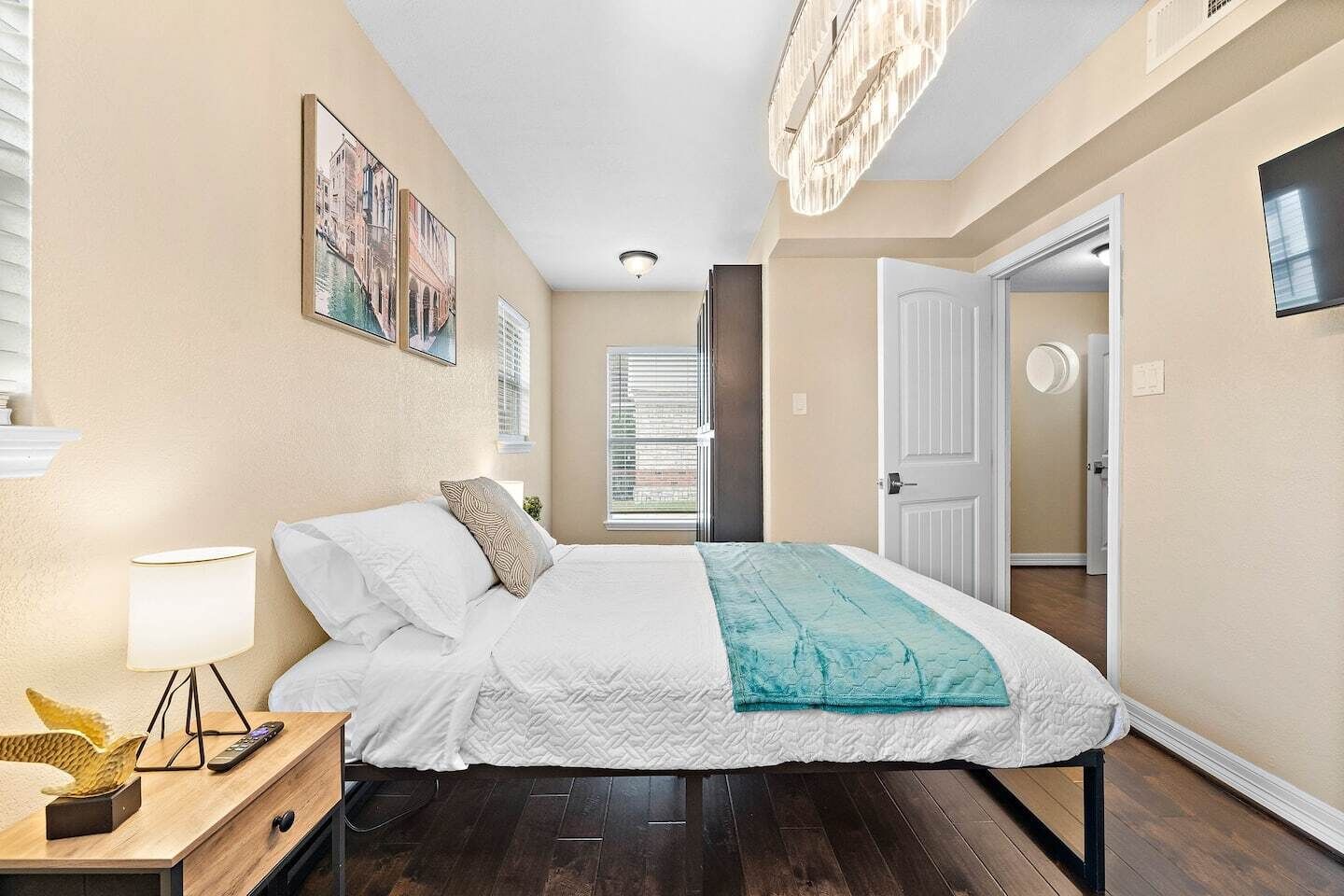 A bedroom with a bed, a nightstand, a lamp, and a window with blinds.