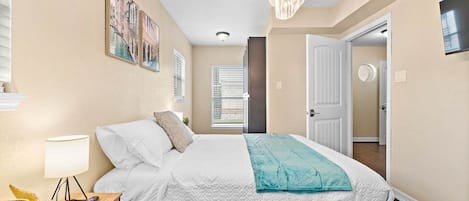 A bedroom with a bed, a nightstand, a lamp, and a window with blinds.