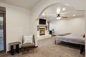 Une chambre avec une cheminée, un lit, une chaise et un téléviseur.