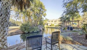 Relax in a serene outdoor setting with a tranquil spot for two, surrounded by lush greenery and a well-maintained lawn.