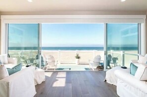 Un salon moderne doté d’une grande porte vitrée donnant sur un balcon avec vue sur la plage.
