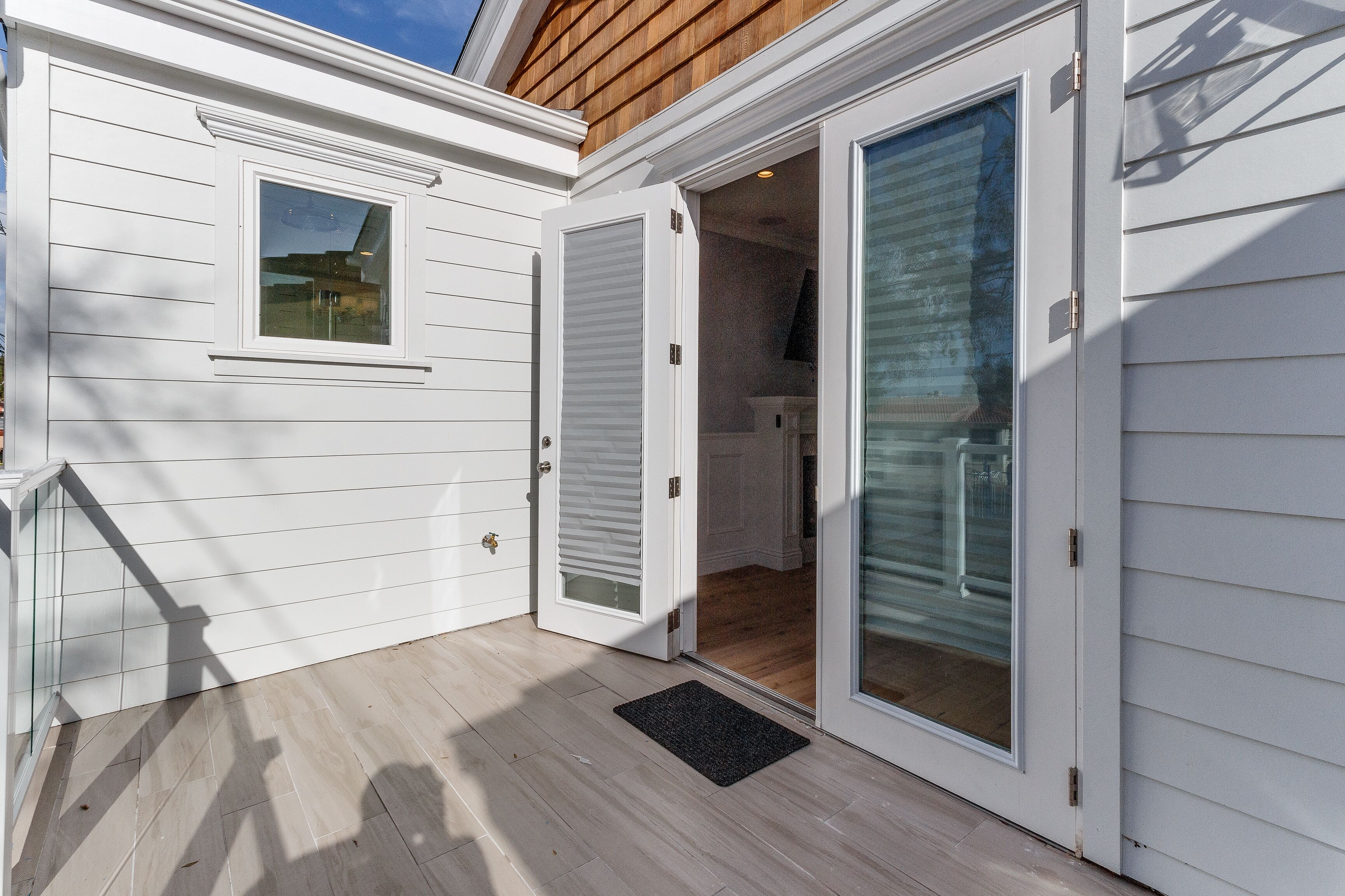 A white exterior with a sliding glass door leading to a covered patio area.
