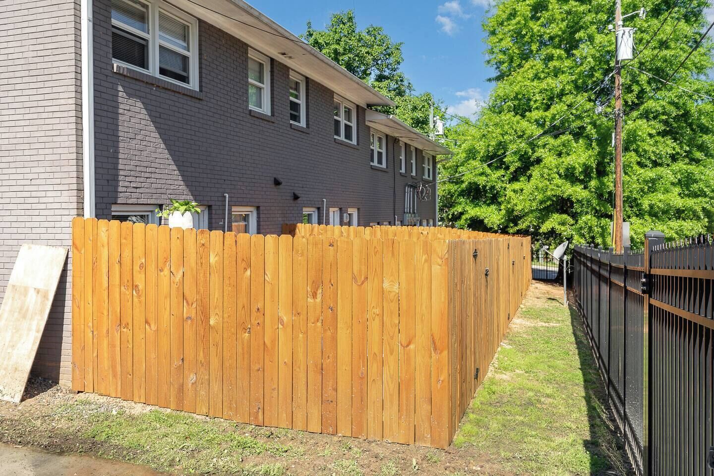 A residential building with a wooden fence and a metal gate.