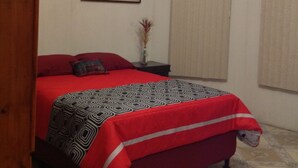 Un dormitorio con una cama, ventilador de techo, un cuadro y una ventana con persianas.