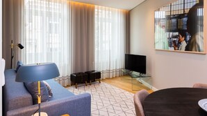 Ett modernt vardagsrum med en soffa, en tv, ett glasbord och en matplats.