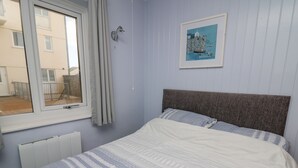 A bedroom with a bed, a window, a radiator, and a framed picture on the wall. - 1 St. Marys Court (Tenby)