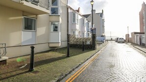 A coastal street with residential buildings, a cobblestone road, and a clear sky. - 1 St. Marys Court (Tenby)