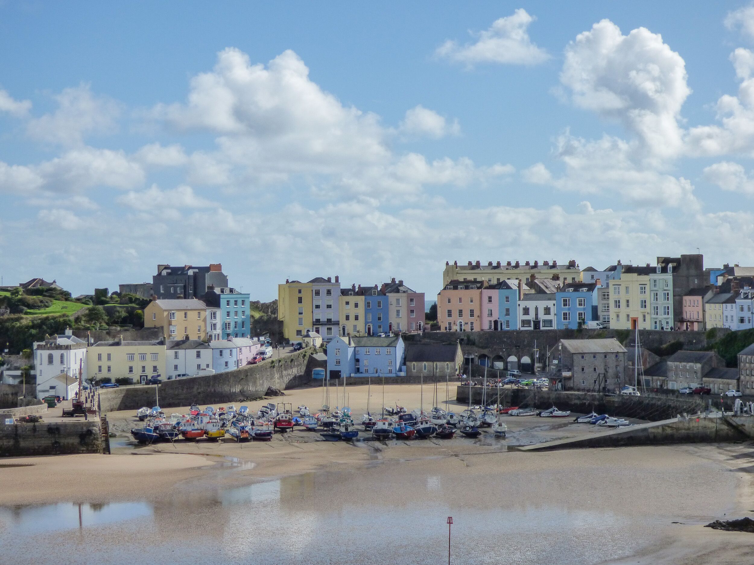 A coastal town with colorful buildings, a sandy beach, and boats docked near the shore.
