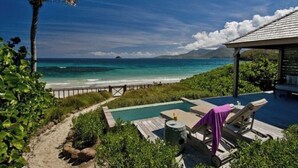 A pool area with lounge chairs and a view of the ocean.