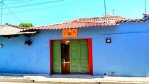 A building with a blue exterior, a red door, and a sign above the door.