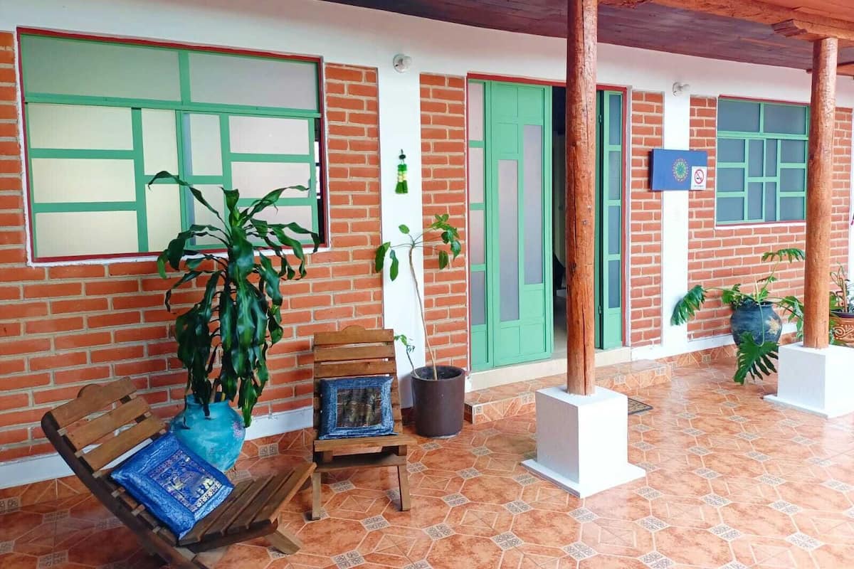 A covered outdoor area with a brick wall, green doors, and tiled flooring.