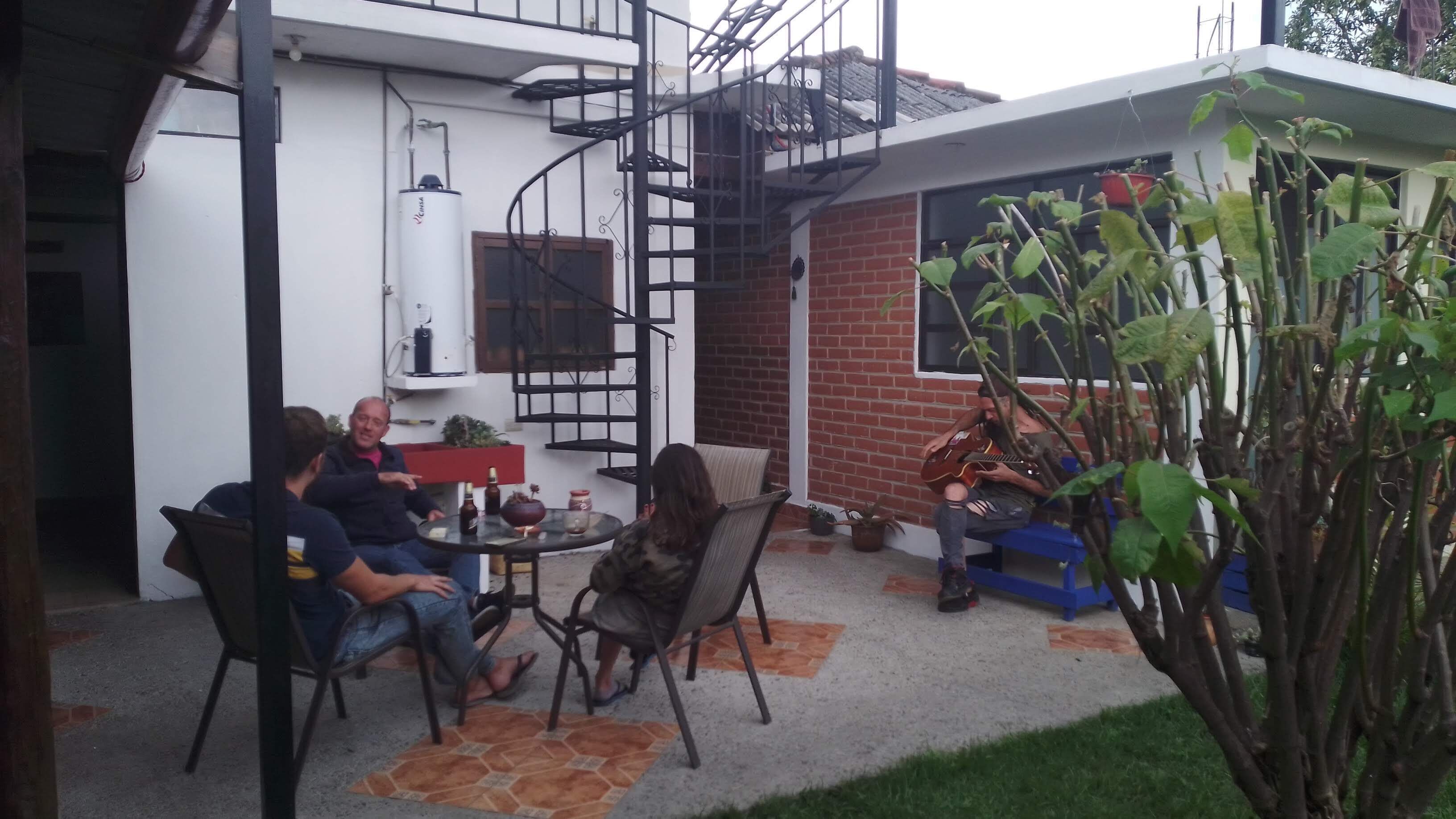 Un patio con un tavolo rotondo e sedie, un muro in mattoni e una persona che suona la chitarra.