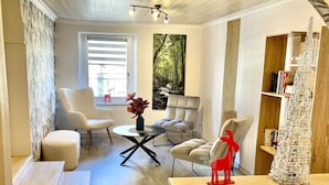 A modern living room with a sofa, chairs, a coffee table, and a bookshelf.