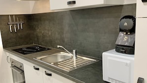 A modern kitchen with a stainless steel range hood, a built-in sink, and a coffee maker.