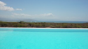 A clear blue pool with a view of a beach and distant mountains. - Altos de la Caobita  (Azua)