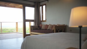A bedroom with a bed, a nightstand, a lamp, a window, and a view of the outdoors. - Altos de la Caobita  (Azua)