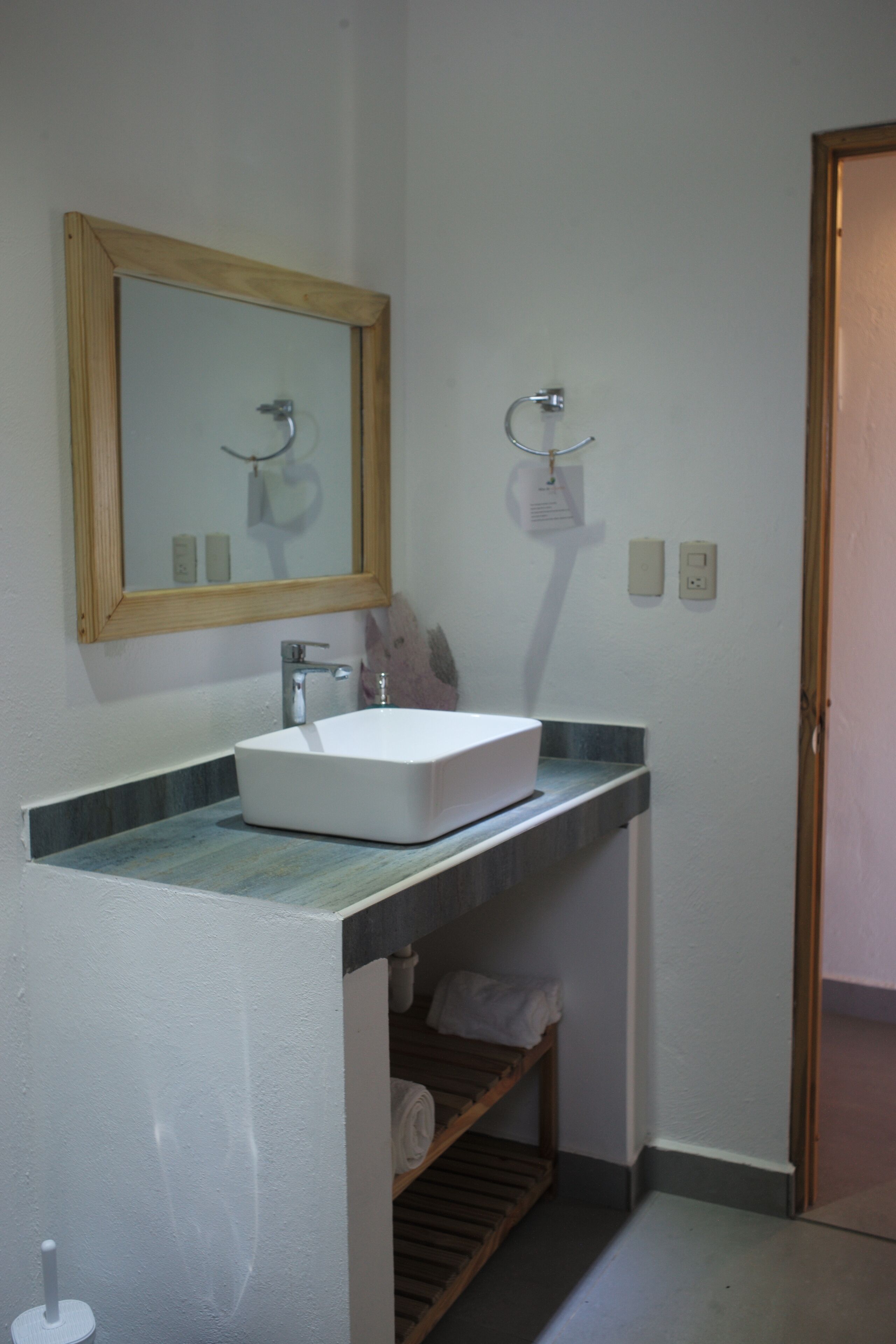 A bathroom with a white sink, a wooden-framed mirror, and a towel rack.