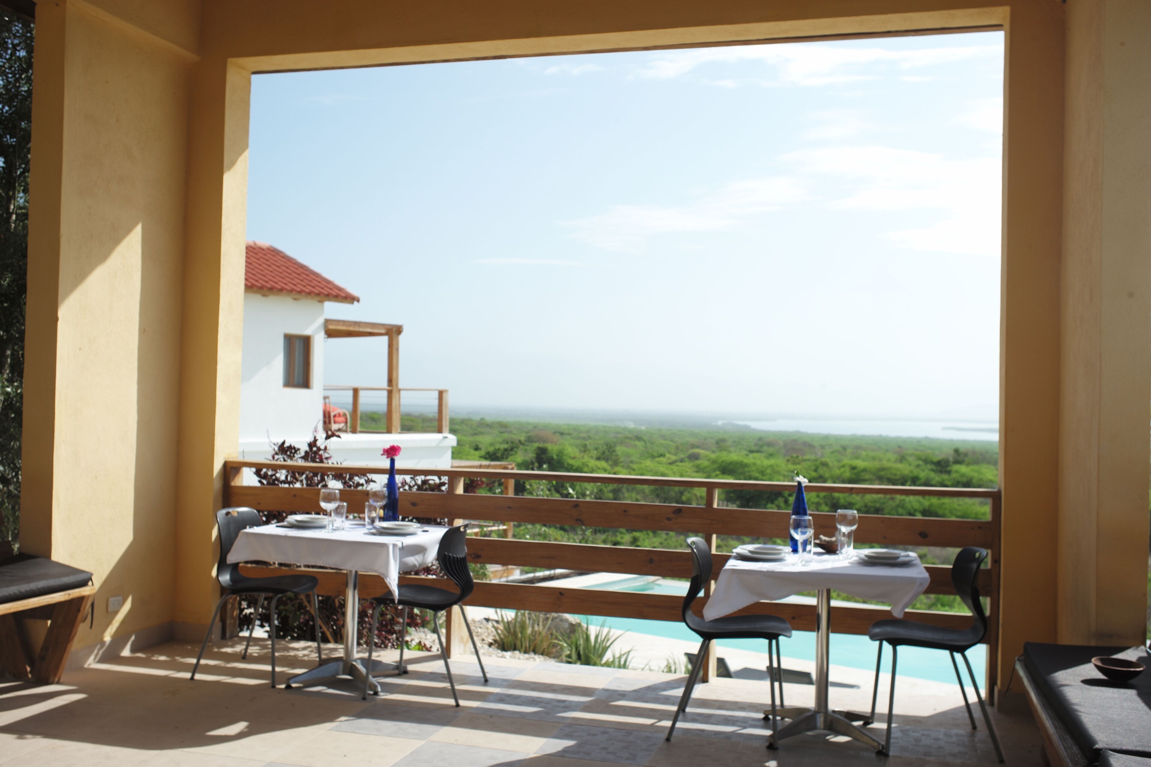 An outdoor dining area with a table set for two, overlooking a scenic landscape.