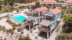 A resort with multiple buildings, a swimming pool, and a mountainous backdrop. - Altos de la Caobita  (Azua)