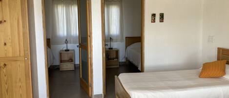 Une chambre à coucher avec un lit en bois, une table de chevet, un miroir et une armoire.