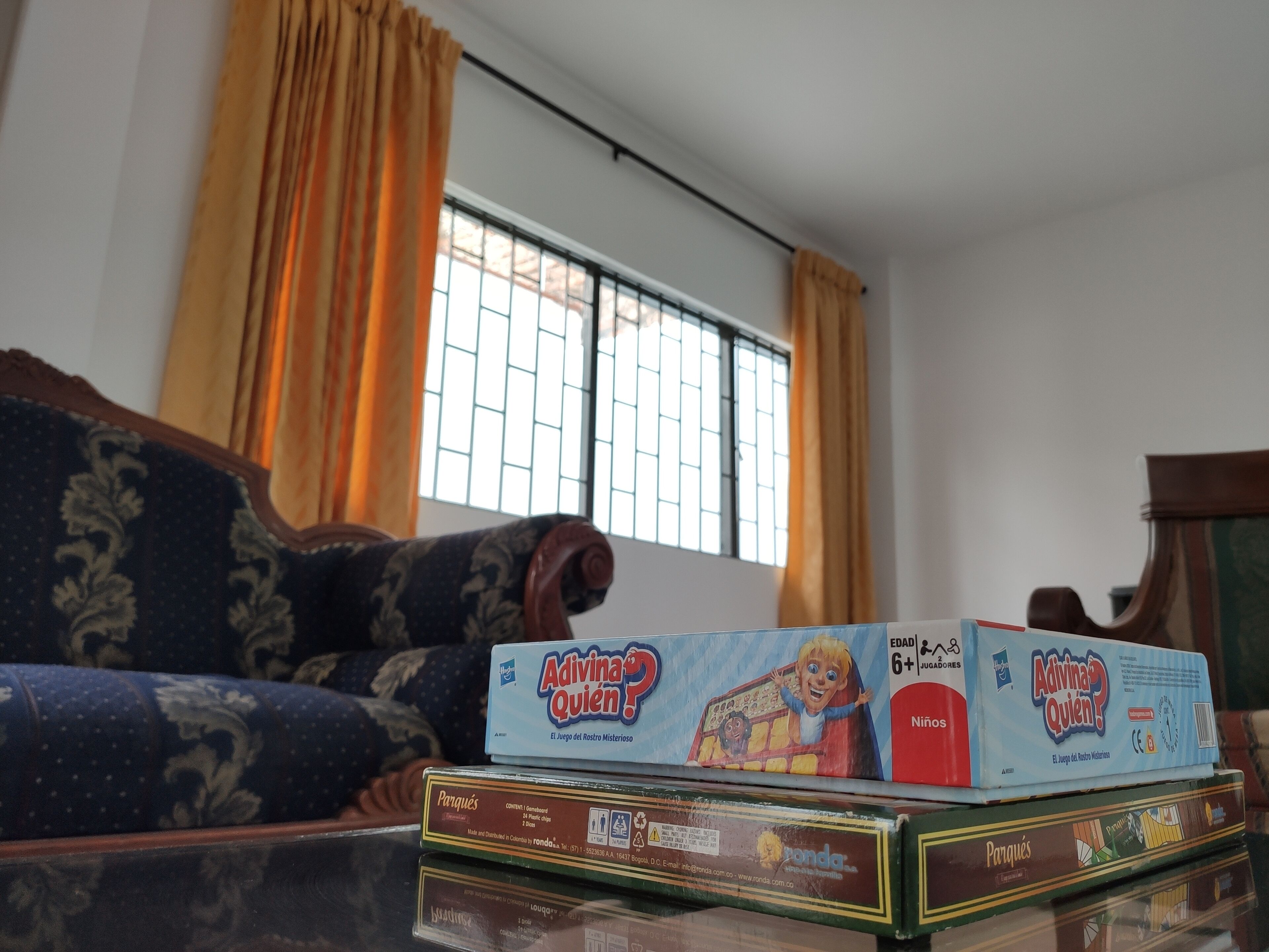 Una sala de estar con un sofá, una ventana con rejas y varios juegos de mesa sobre una mesa.