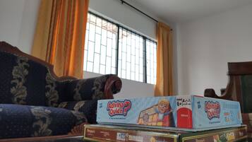 Una sala de estar con un sofá, una ventana con rejas y varios juegos de mesa sobre una mesa.