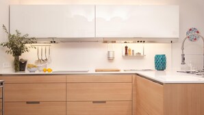 Una cocina moderna con armarios de madera, encimera blanca y grifo de acero inoxidable.