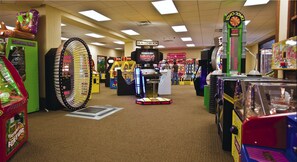 Eine Spielhalle mit verschiedenen Spielautomaten, darunter ein großes Glücksrad und ein Spielgerät namens 'Gorilla King'.