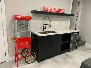 Eine Küchenzeile mit einem roten Popcorntisch, einem schwarzen Schrank, einem Edelstahlkühlschrank und einer Marmor-Spritzschutzwand.