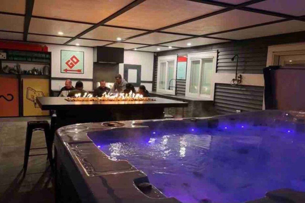 A room with a hot tub, a bar area, and a group of people seated around a table.