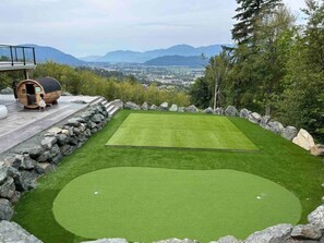 Ein Golf-Putting-Green mit einer Steinmauer und einer Holzbottich-Konstruktion.