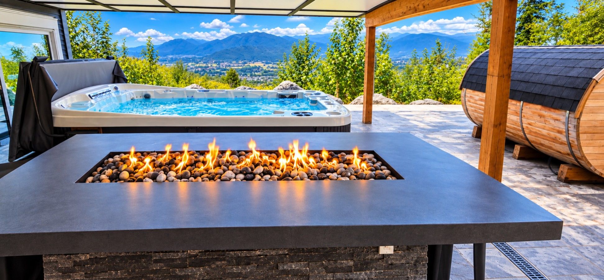 A hot tub with a mountain view, a fire feature with stones, and a wooden barrel.