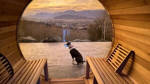 Una cabaña de madera con un ventanal circular que ofrece vistas de un paisaje montañoso.